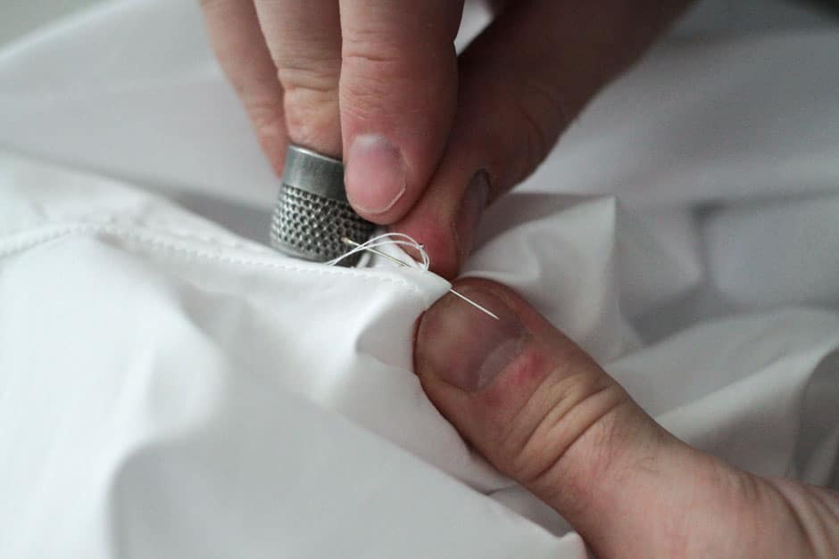 Mother-of-pearl button of a bespoke dress shirt attached by hand
